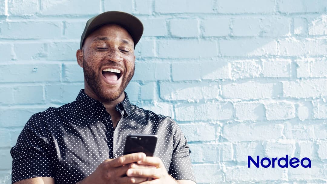 Smilende mann som ser på mobilen, med Nordea-logoen