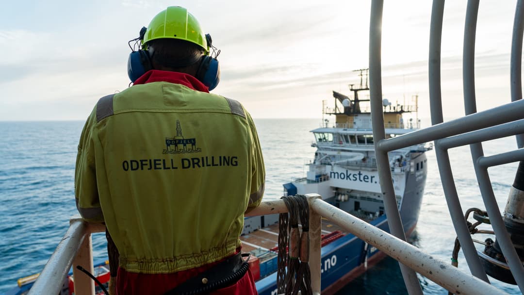 Arbeider i Odfjell Drilling-kjeledress ved rekkverket, med havet nedenfor