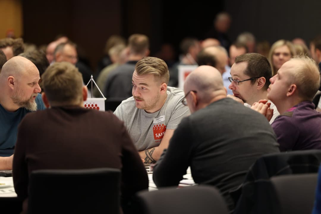 Medlemmer i samtale rundt et bord på en samling i SAFE